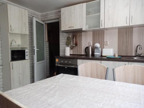 a kitchen with white cabinets and a table and chairs at Guest House 51 in Kranevo