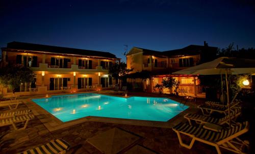 a swimming pool at night with chairs and a building at Toni´s Guesthouse in Kavos