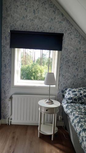 a bedroom with a window and a table with a lamp at Nytorpsgården in Arbrå