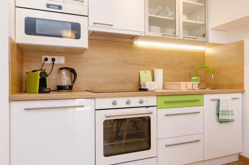 a kitchen with white cabinets and a stove top oven at La Bella Centrum Apartmanok Kék Zöld in Hévíz