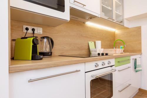 a kitchen with white cabinets and a yellow appliance at La Bella Centrum Apartmanok Kék Zöld in Hévíz