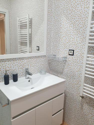 La salle de bains est pourvue d'un lavabo blanc et d'un miroir. dans l'établissement Apartamento Campomar Garaje incluido, à Castro Urdiales