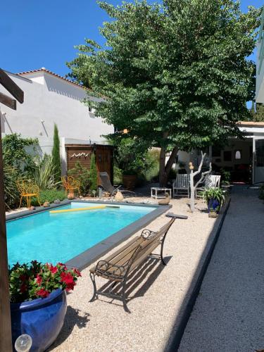 una piscina con un banco y un árbol en Appartement dans maison d'artiste en Lunel