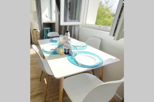 - une table à manger et des chaises blanches dans une chambre avec fenêtre dans l'établissement KITESURF - 100M PLAGE - DECO DESIGN, à Berck-sur-Mer