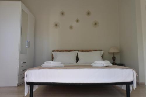 a white bedroom with a large bed with two pillows at Mina's serene garden house in Kontokali