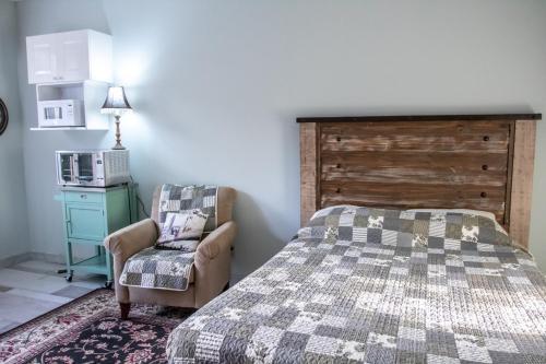 a bedroom with a bed and a chair and a microwave at The Jypsy Inn / Fifth Avenue in Bracebridge