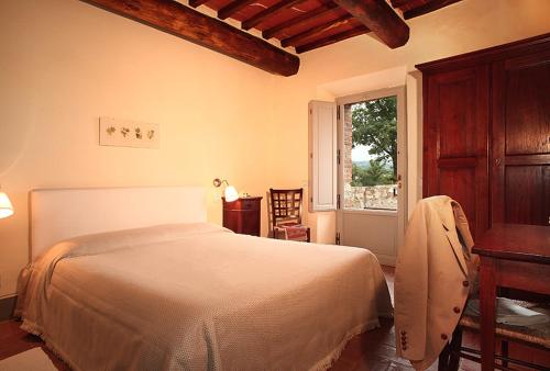 a bedroom with a bed and a table and a window at Agriturismo Podere La Casa in Montalcino