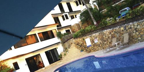 a view of a swimming pool in front of a building at Villa Palmitas acogedor departamento nivel piscina gigante jardines in Acapulco