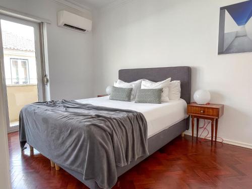 Un dormitorio con una gran cama blanca y una ventana en Claude Homes Lisbon Rato, en Lisboa