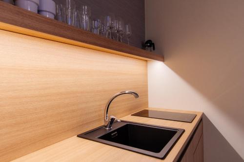 a kitchen with a sink in a wooden cabinet at Apartmán C317 Hrebienok Resort 2 in Vysoke Tatry - Stary Smokovec