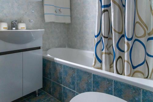 een badkamer met een bad, een toilet en een douchegordijn bij Grigo apartments in Alexandroupoli