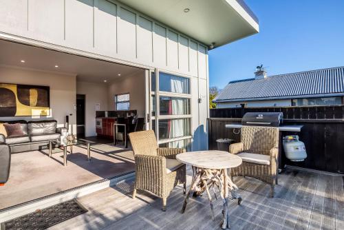 an outdoor patio with a table and chairs and a kitchen at TWO FOUR COLOGNE in Martinborough 