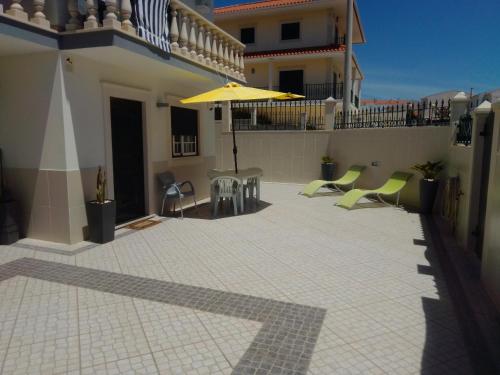 a patio with a table and an umbrella on a building at HOUSEMARIA in Nazaré