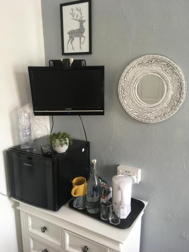 a table with a television and a mirror on a wall at Newburgh Guesthouse in Torquay