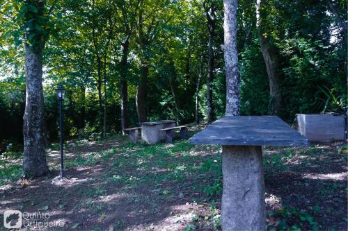 a stone bench in a park with trees at Quinta da Urtigueira in Felgueiras