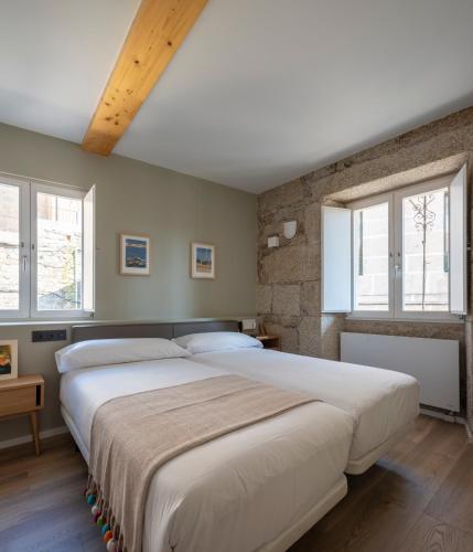 two beds in a bedroom with two windows at Casa das Trabancas in Tui
