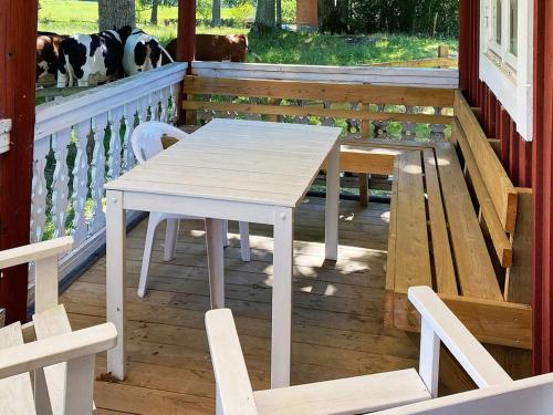 una mesa blanca y sillas en un porche con un perro en 4 person holiday home in VETLANDA en Vetlanda