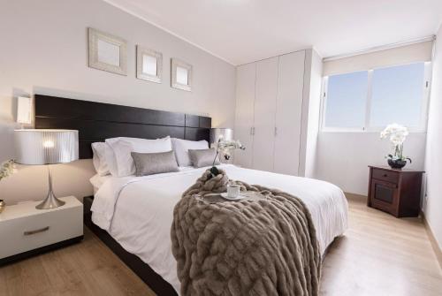a bedroom with a large bed with a blanket on it at Skyliving Towers Apartments - Perú in Lima