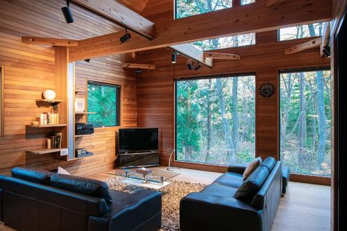 a living room with two couches and a television in a forest at Phoenix Chalets by HHG in Hakuba