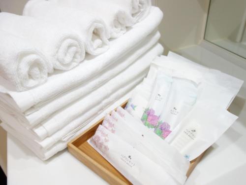 a tray of white towels and a pile of towels at サンライン北谷コンドミニアムリゾート in Chatan