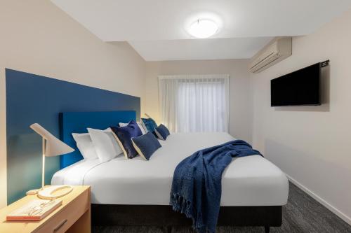 a hotel room with a bed, chair, and nightstand at Quest Geelong in Geelong