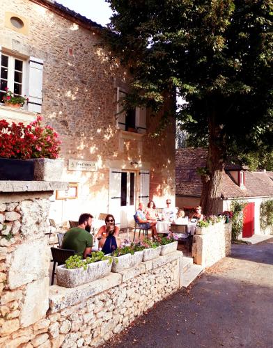 Les Cèdres في Saint-Marcel-du-Périgord: مجموعة من الناس يجلسون على طاولات خارج مبنى