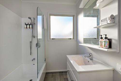 a white bathroom with a sink and a shower at The White Morph - Heritage Collection in Kaikoura