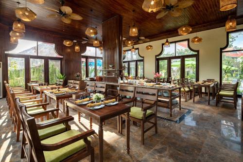 a restaurant with wooden tables and chairs and windows at Bai Dinh Riverside Resort & Spa in Ninh Binh