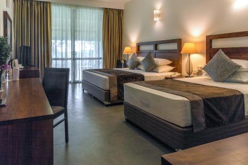 um quarto de hotel com duas camas e uma secretária em Earls Rajarata em Anuradhapura