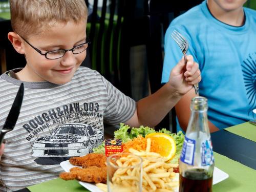 a young boy sitting at a table with a plate of food at 6 person holiday home in Skærbæk-By Traum in Skærbæk