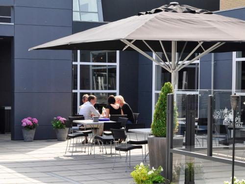 a group of people sitting at a table under an umbrella at 6 person holiday home in Skærbæk-By Traum in Skærbæk