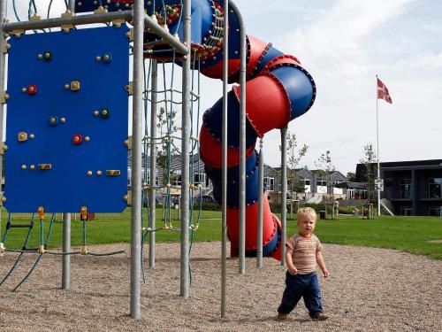 a young boy standing in front of a playground at 6 person holiday home in Skærbæk-By Traum in Skærbæk