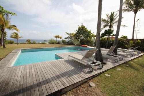 - une piscine avec 2 chaises longues sur une terrasse en bois dans l'établissement Villas Karukera - Hamak Coco Caraibes, à Kahouanne