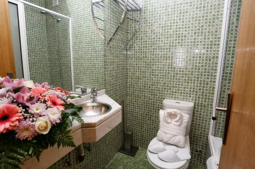 baño con lavabo, aseo y flores en Oporto City Centre Apartments, en Oporto