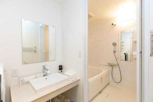 y baño blanco con lavabo y ducha. en Villa Roppongi, en Tokio