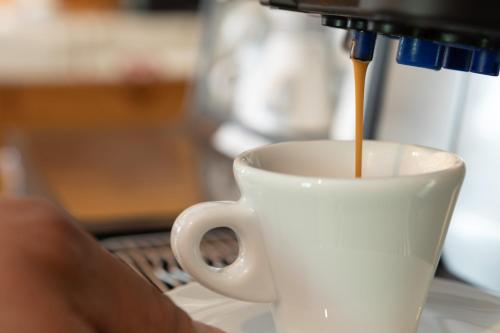 a person is pouring coffee into a coffee cup at Hotel Meuble' Joli in Breuil-Cervinia