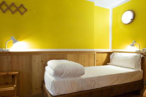 a bedroom with a bed with yellow walls and two lights at Hotel Meuble' Joli in Breuil-Cervinia