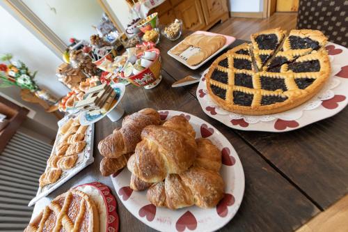 a table topped with plates of pastries and a pie at Hotel Meuble' Joli in Breuil-Cervinia