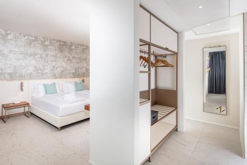 a white bedroom with a bed and a mirror at THE ONE CAORLE - Hotel & Apartments in Caorle