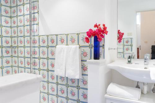 a bathroom with a sink and a vase of flowers on the wall at Villa Castello Apartments in Capri