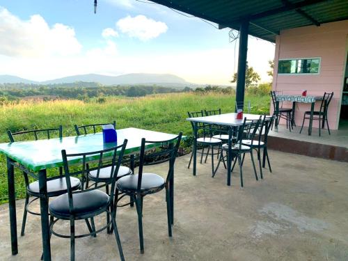 a group of tables and chairs with mountains in the background at บ้านวนัชชา รีสอร์ท in Wang Nam Khieo