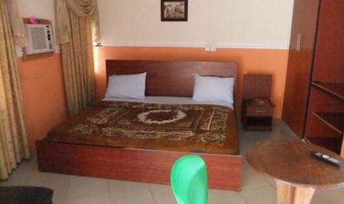 1 dormitorio con 1 cama grande con silla verde en Ade Super Hotel Single, en Akure