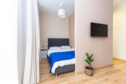a bedroom with a bed and a flat screen tv at Люкс апартаменты в самом центре Перми in Perm