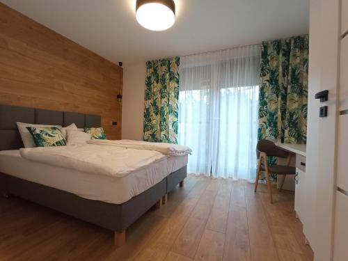 a bedroom with a bed and a desk and a window at Apartamenty Woda i Las in Turawa