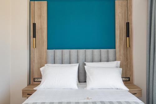 a bed with two white pillows and a blue wall at Sapphire Blue Suites in Kissamos