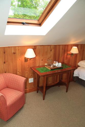 a bedroom with a table and a bed and a window at Evergreen Lodge in Stellenbosch
