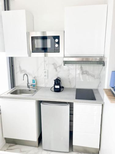 une cuisine blanche avec un évier et un micro-ondes dans l'établissement Halévy Résidence, à Nice