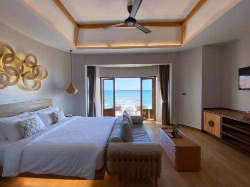 a bedroom with a large bed and a view of the ocean at Maldives Beach Resort in Chao Lao Beach