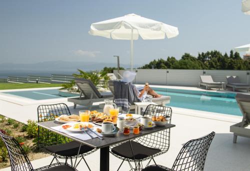 stół z jedzeniem obok basenu w obiekcie Terra Olivia Luxury Villas and Suites w mieście Paliouri
