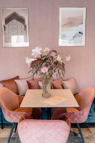 a vase of flowers on a table with chairs at Jeanne in Nieuwpoort